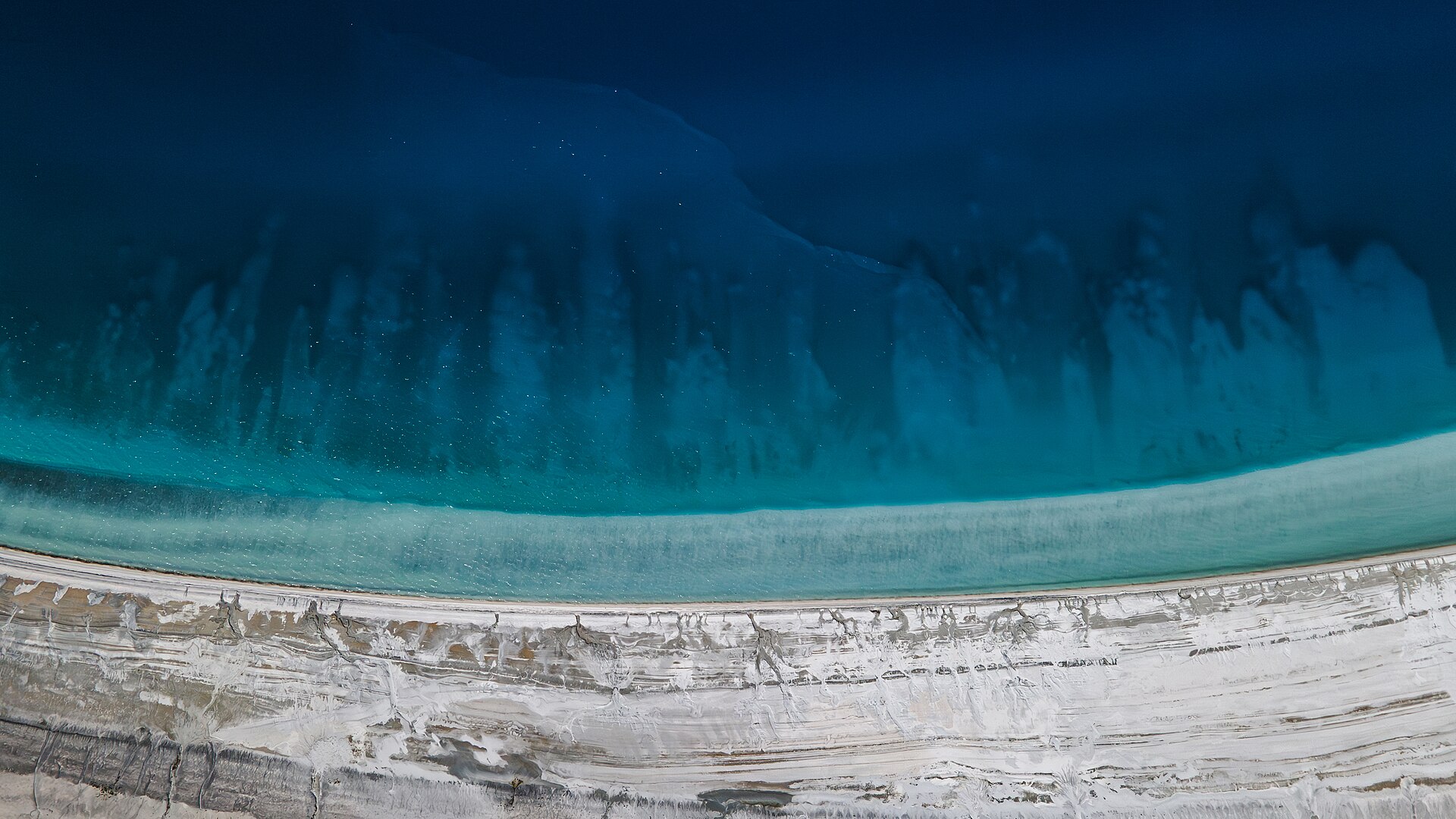 Aerial view of Lake Salda's deep blue water, turquoise shallows and white mineral shoreline