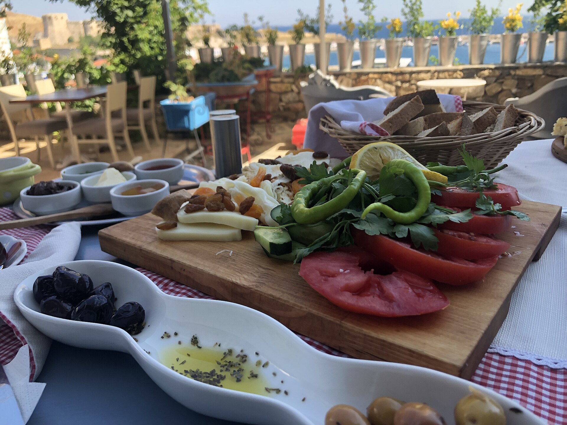 A Turkish breakfast table with bread, cheese, olives, tomatoes, peppers, herbs and small dishes beside the Aegean coast