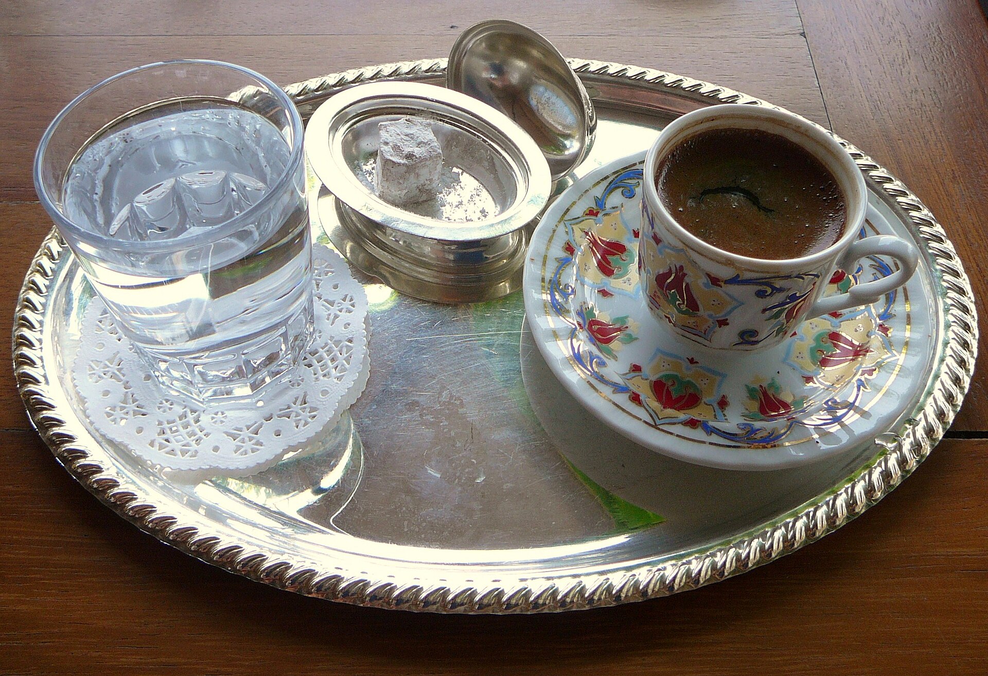 Turkish coffee served with a glass of water and lokum on a metal tray